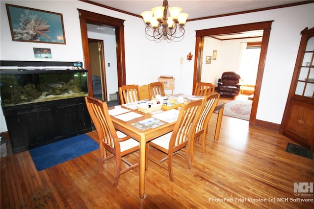 dining area with ornamental molding, a chandelier, and hardwood / wood-style flooring