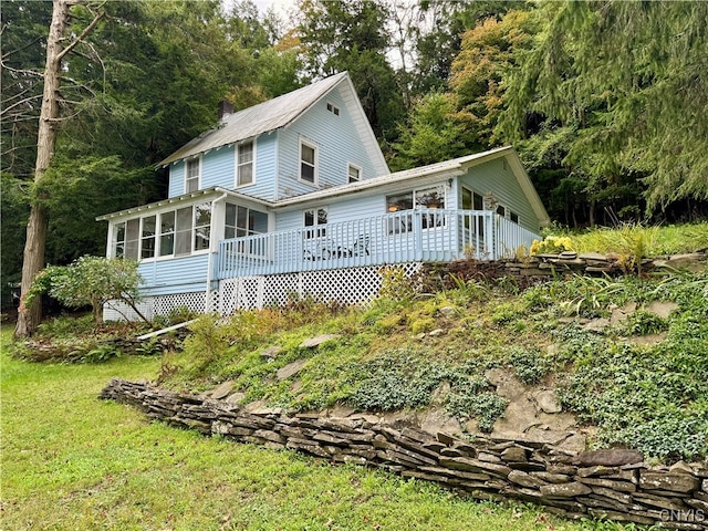 view of front of property featuring a sunroom, a front lawn, and a wooden deck