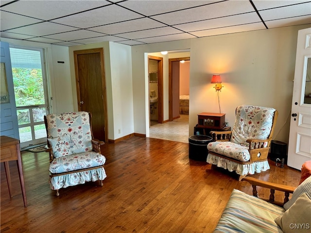 living area with a paneled ceiling and hardwood / wood-style floors