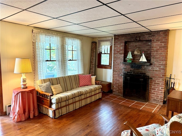 living room with wood-type flooring, a fireplace, a baseboard radiator, and a wealth of natural light