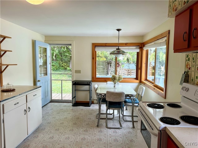 kitchen with white electric stove, hanging light fixtures, and a healthy amount of sunlight