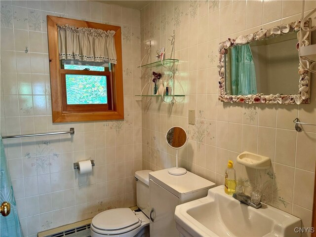 bathroom featuring sink, tile walls, baseboard heating, and toilet