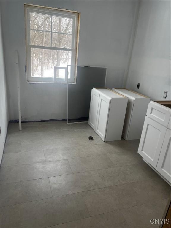 clothes washing area with light tile patterned floors