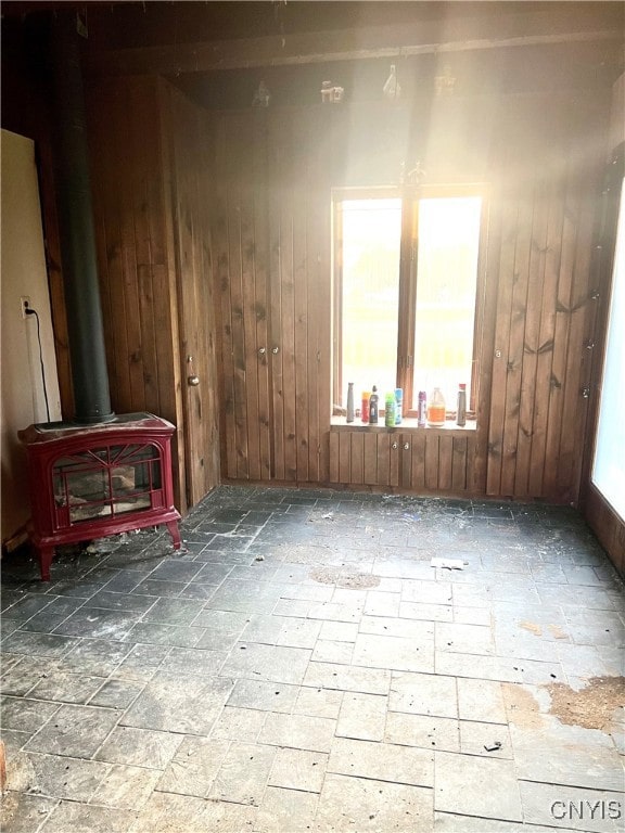 spare room featuring a wood stove and wood walls