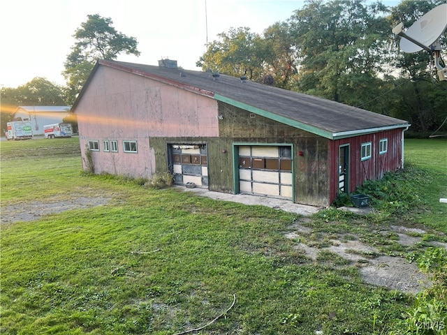 view of outdoor structure featuring a garage and a lawn