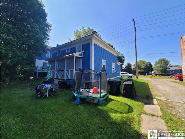 back of house featuring a lawn and a trampoline