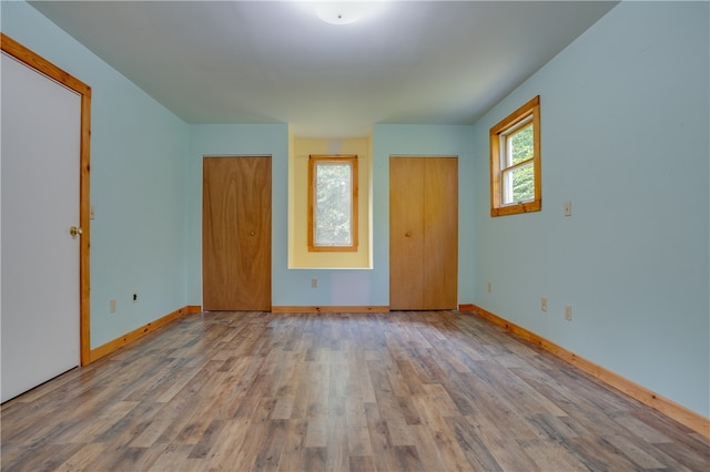 unfurnished bedroom with multiple closets and light wood-type flooring