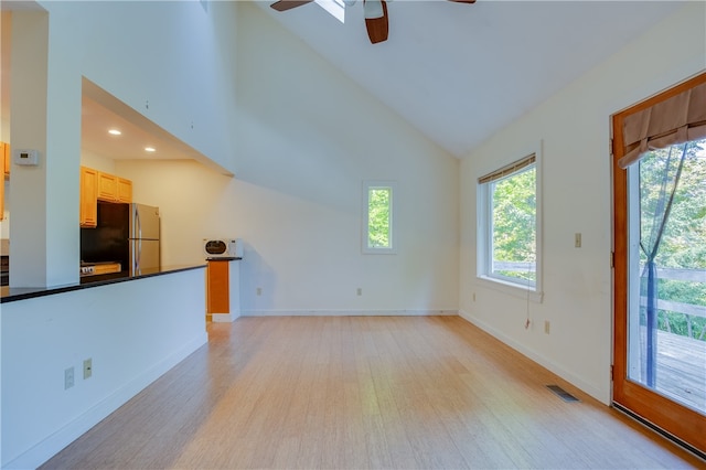 unfurnished living room featuring light wood-type flooring, ceiling fan, and high vaulted ceiling