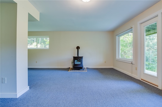 unfurnished living room with a wood stove and carpet floors