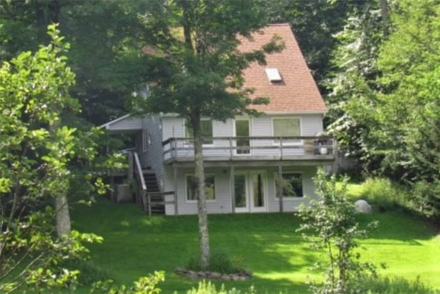 back of property featuring a deck and a lawn