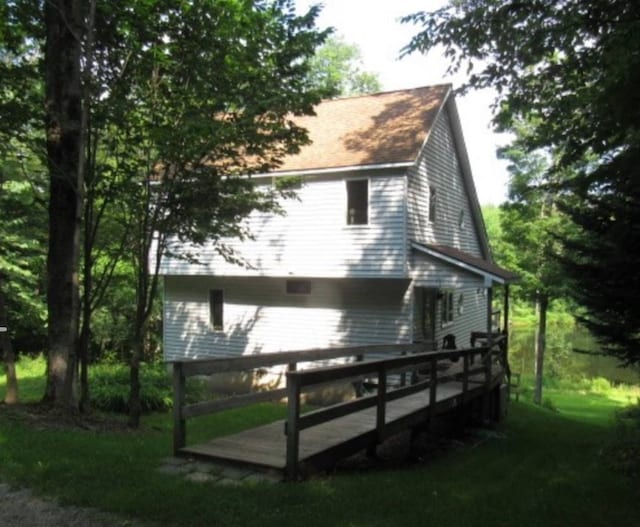 rear view of property featuring a deck and a lawn