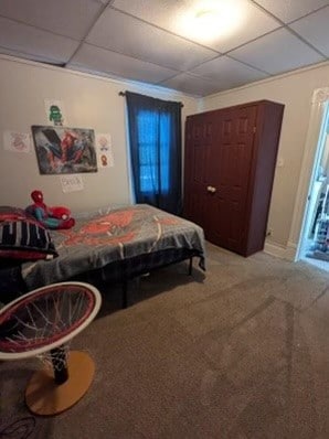 carpeted bedroom featuring a drop ceiling