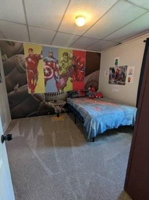 bedroom featuring a drop ceiling and carpet floors