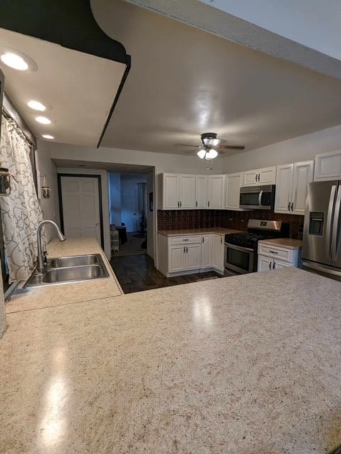 kitchen with stainless steel appliances, white cabinets, ceiling fan, and sink