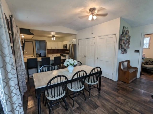 dining space with ceiling fan, dark hardwood / wood-style floors, and vaulted ceiling