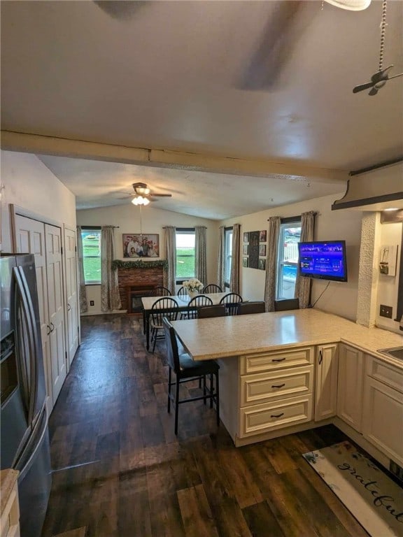 kitchen with ceiling fan, lofted ceiling, kitchen peninsula, and a breakfast bar