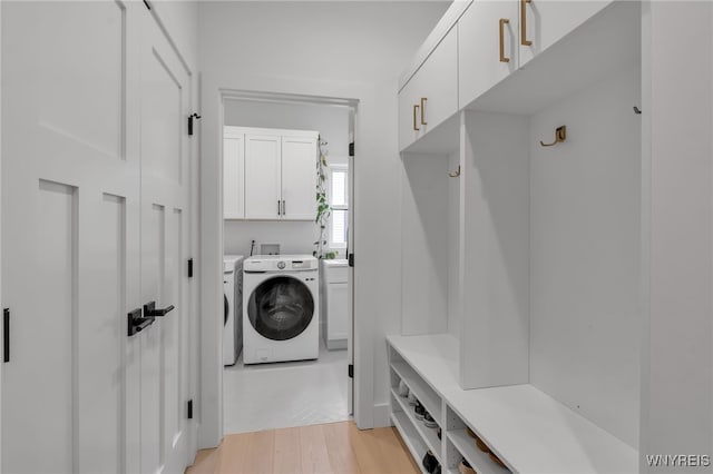 laundry room with washer and dryer, light hardwood / wood-style flooring, and cabinets