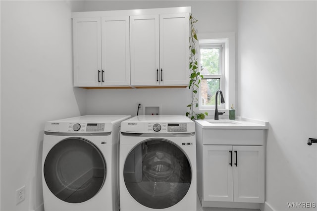 washroom with washing machine and clothes dryer, cabinets, and sink