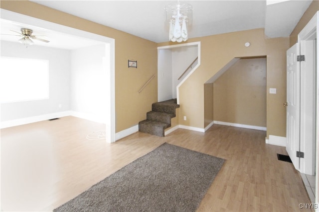 foyer entrance with ceiling fan with notable chandelier and light wood-type flooring