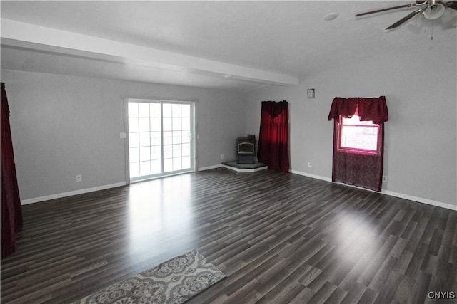 unfurnished room with a wood stove, ceiling fan, beamed ceiling, and dark hardwood / wood-style floors