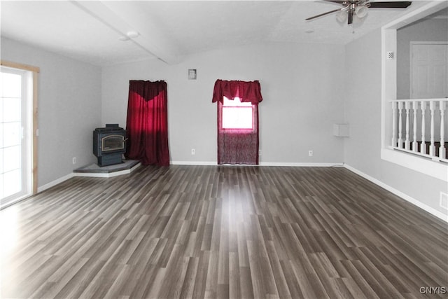 spare room featuring vaulted ceiling with beams, ceiling fan, dark wood-type flooring, and a wood stove