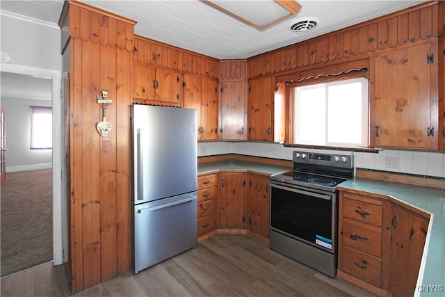 kitchen with tasteful backsplash, wooden walls, electric range, hardwood / wood-style flooring, and stainless steel refrigerator