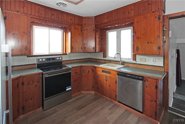 kitchen featuring sink, dark wood-type flooring, electric range oven, tasteful backsplash, and stainless steel dishwasher