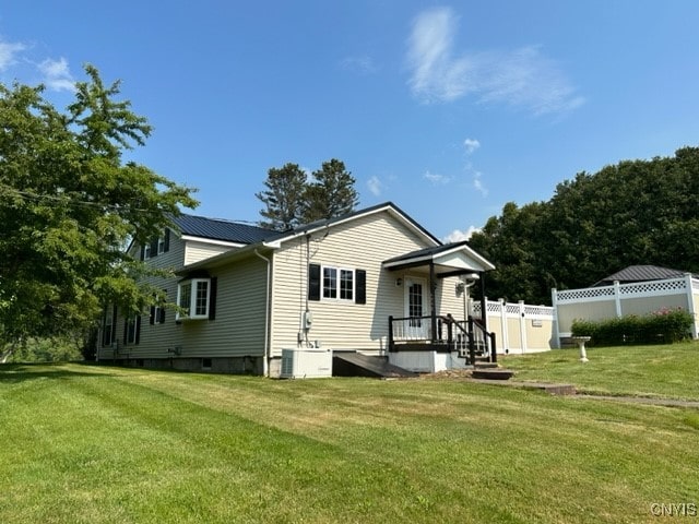 rear view of house with central AC and a yard