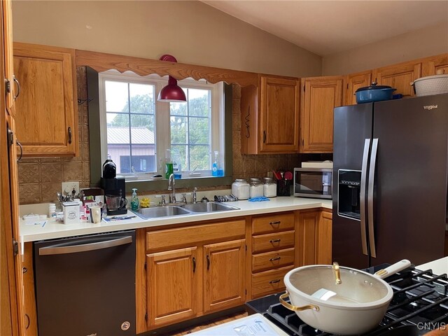 kitchen with backsplash, lofted ceiling, appliances with stainless steel finishes, and sink