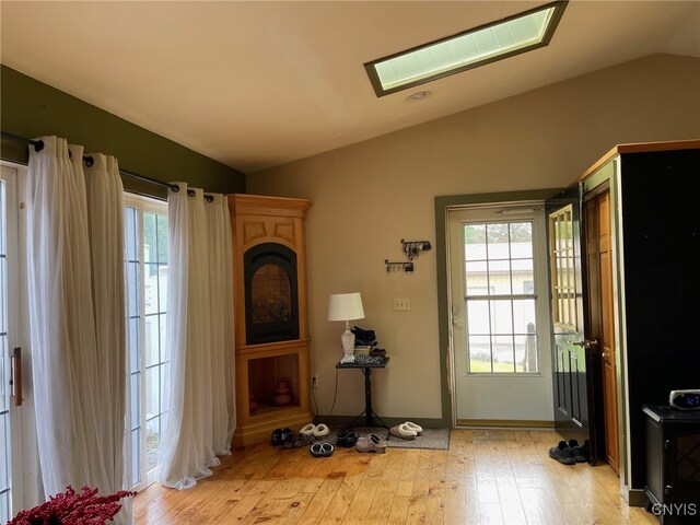 entryway with light hardwood / wood-style flooring and lofted ceiling with skylight