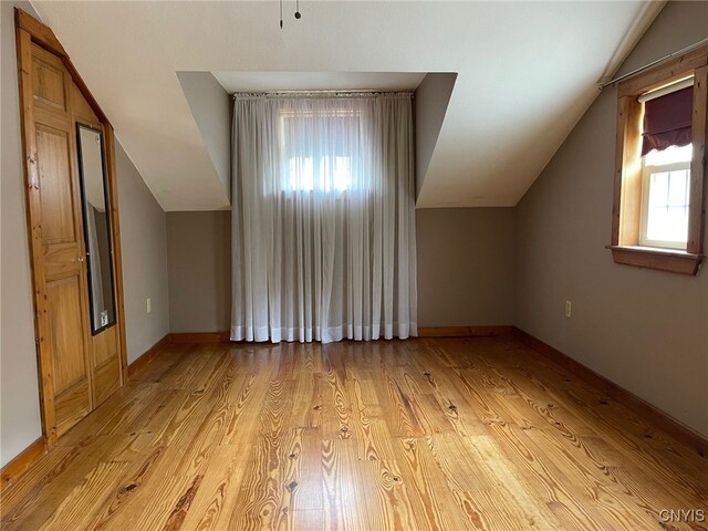 bonus room featuring light wood-type flooring, lofted ceiling, and plenty of natural light