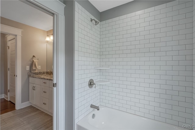 bathroom with hardwood / wood-style floors, vanity, and tiled shower / bath