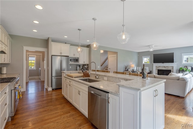 kitchen featuring pendant lighting, a center island with sink, sink, ceiling fan, and appliances with stainless steel finishes