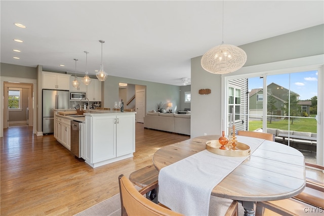 dining space with ceiling fan and light hardwood / wood-style flooring