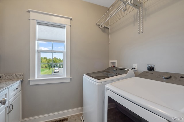 clothes washing area featuring cabinets and washing machine and clothes dryer