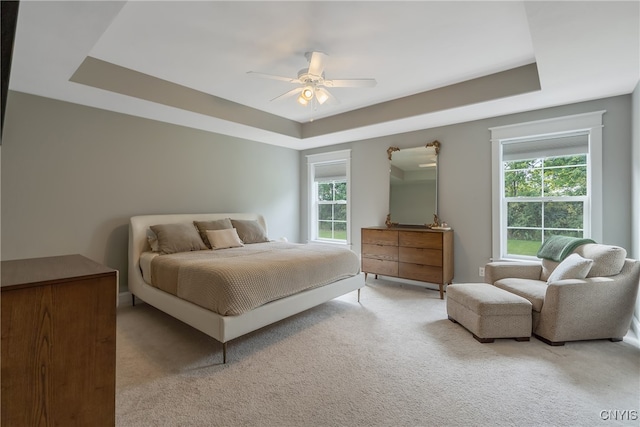 carpeted bedroom with a tray ceiling and ceiling fan