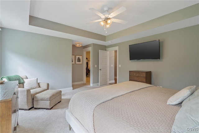 carpeted bedroom featuring a raised ceiling and ceiling fan