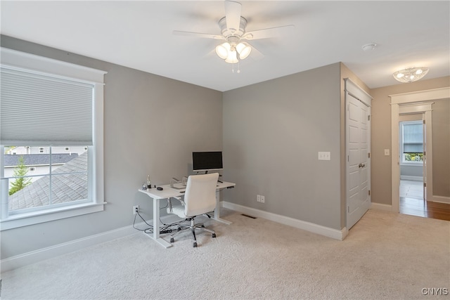 office area with light carpet, ceiling fan, and a healthy amount of sunlight