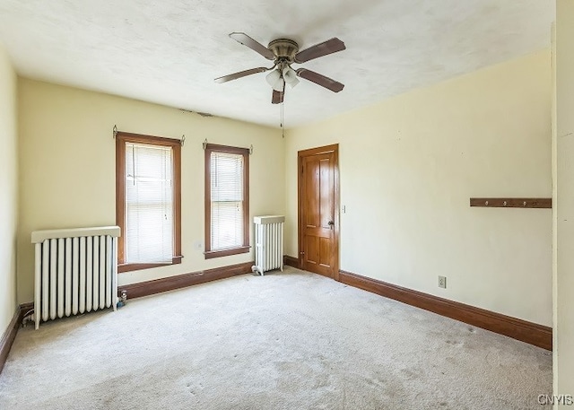 carpeted spare room with radiator and ceiling fan