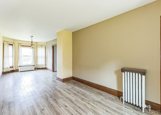 unfurnished room featuring light wood-type flooring and radiator heating unit