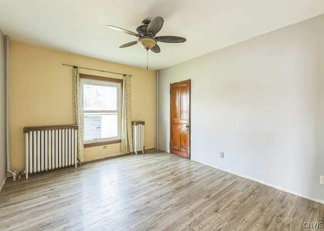 unfurnished bedroom with light wood-type flooring, radiator, and ceiling fan