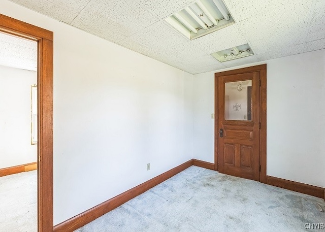 carpeted empty room featuring a paneled ceiling