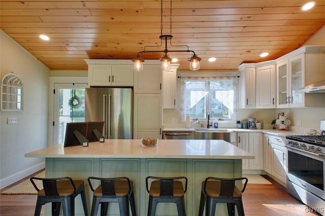 kitchen featuring a center island, white cabinetry, hanging light fixtures, light hardwood / wood-style flooring, and stainless steel appliances