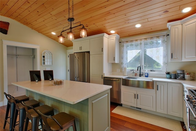 kitchen with a breakfast bar, high quality appliances, hanging light fixtures, and a kitchen island