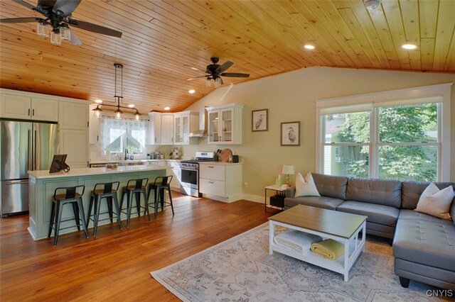 living room with ceiling fan, wooden ceiling, and a healthy amount of sunlight