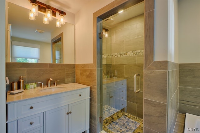 bathroom featuring tile walls, vanity, and a shower with shower door