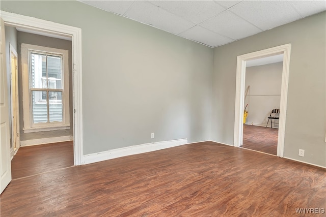 empty room with a drop ceiling and dark hardwood / wood-style flooring