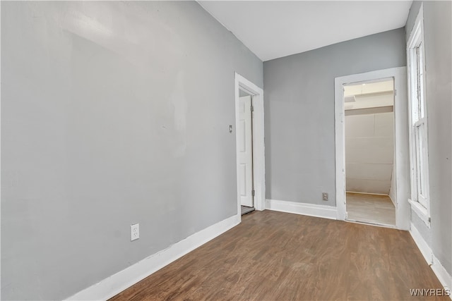 unfurnished bedroom featuring wood-type flooring, a walk in closet, and a closet