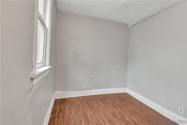 spare room featuring wood-type flooring and crown molding