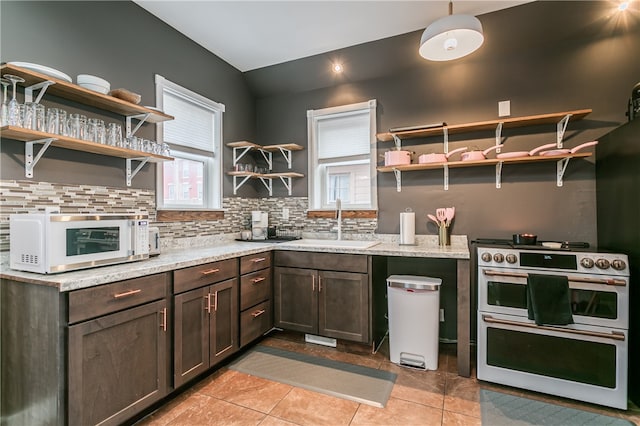 kitchen featuring light tile patterned floors, light stone countertops, sink, and double oven range